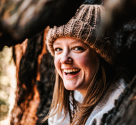 young woman smiling by a tree